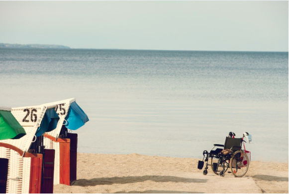 Image of an empty wheelchair on a beach.