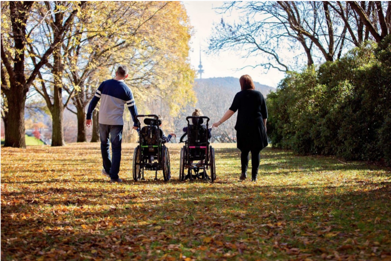 Image of two wheel-chair bound children with their parents.