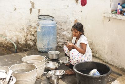Girl sitting on the floor washing tin dishes