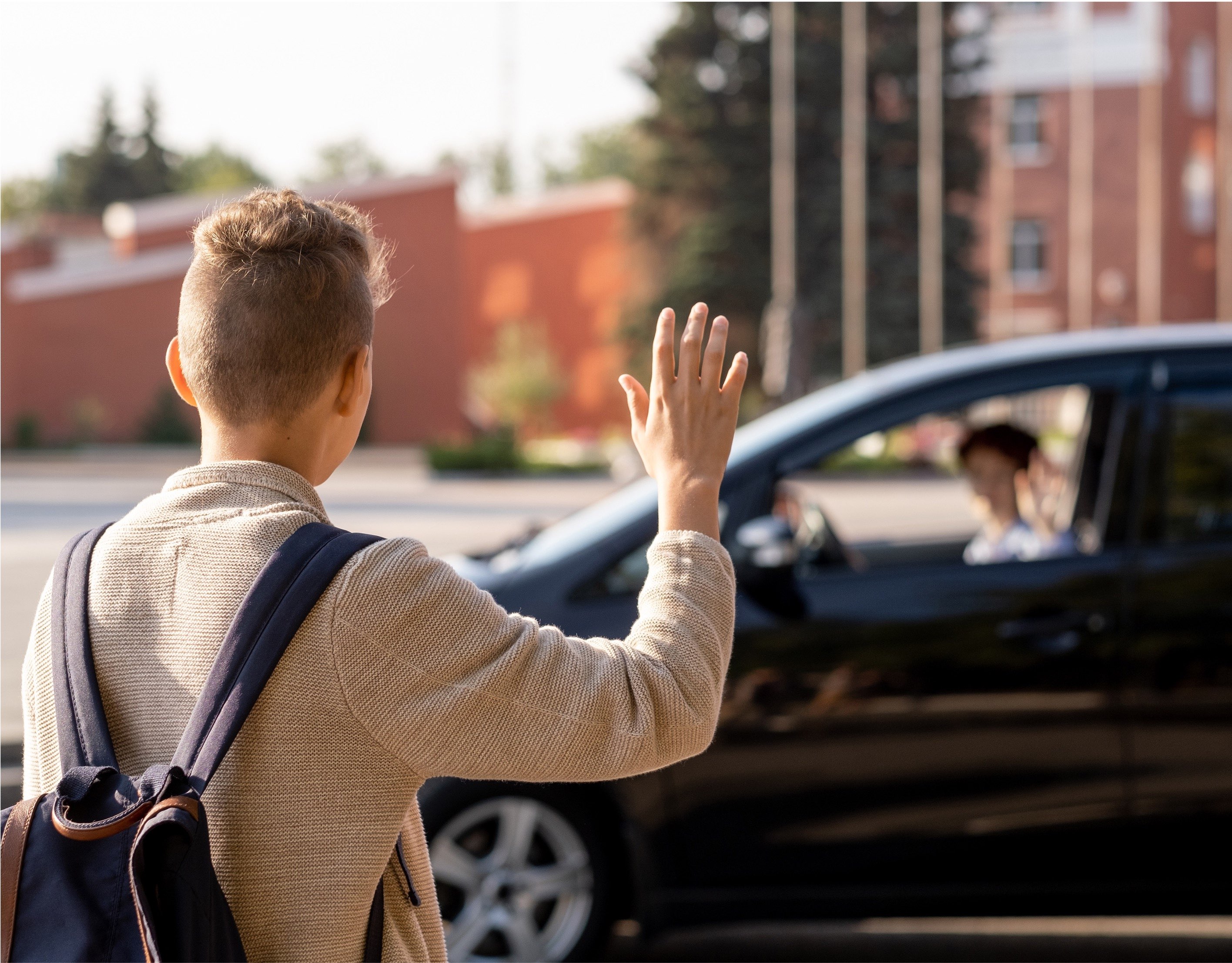 Child waving at parent in car