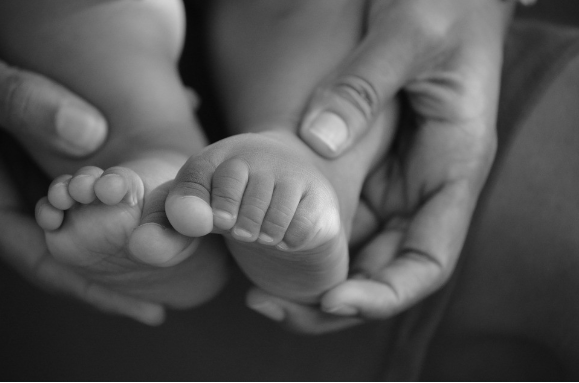 Close-up image of an infant's feet being cradled by an adult.