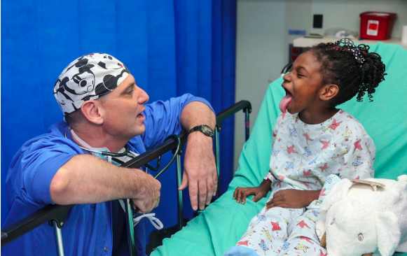 Image of a doctor examining the throat of a young girl in a hospital.