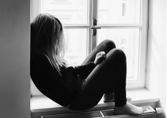 Image of a young teen sitting at window sill.