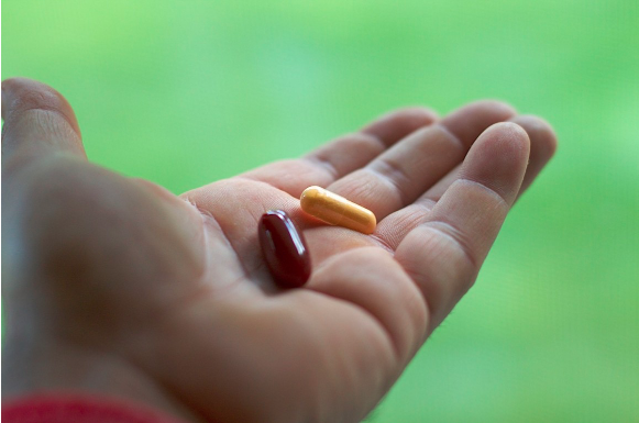 Close-up image of a hand holding two capsules.