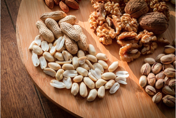Stock photo of a wooden board with different types of nuts on it.