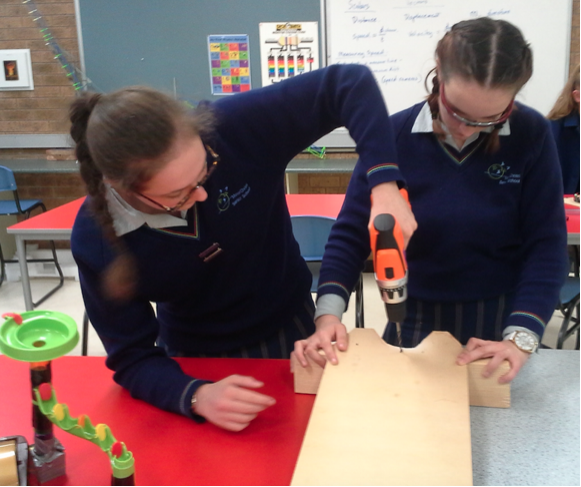Image of two students from Mater Christi College working on their spaghetti machine.