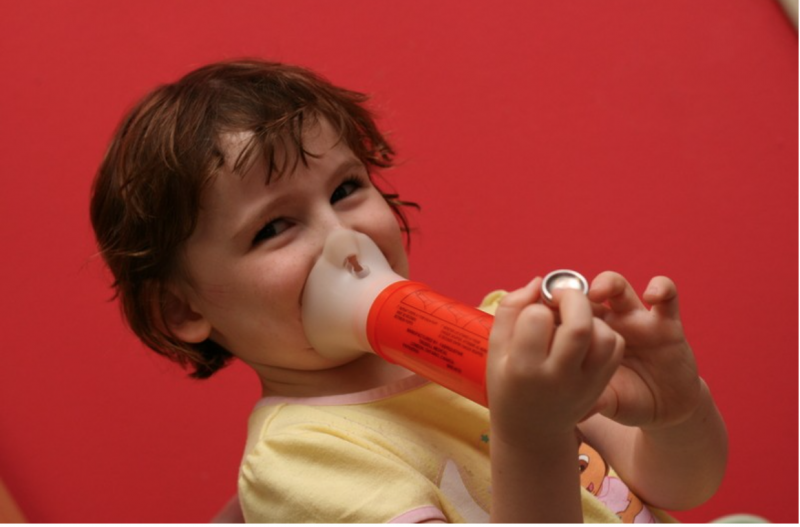 Image of a small child testing their lung capacity with a device.