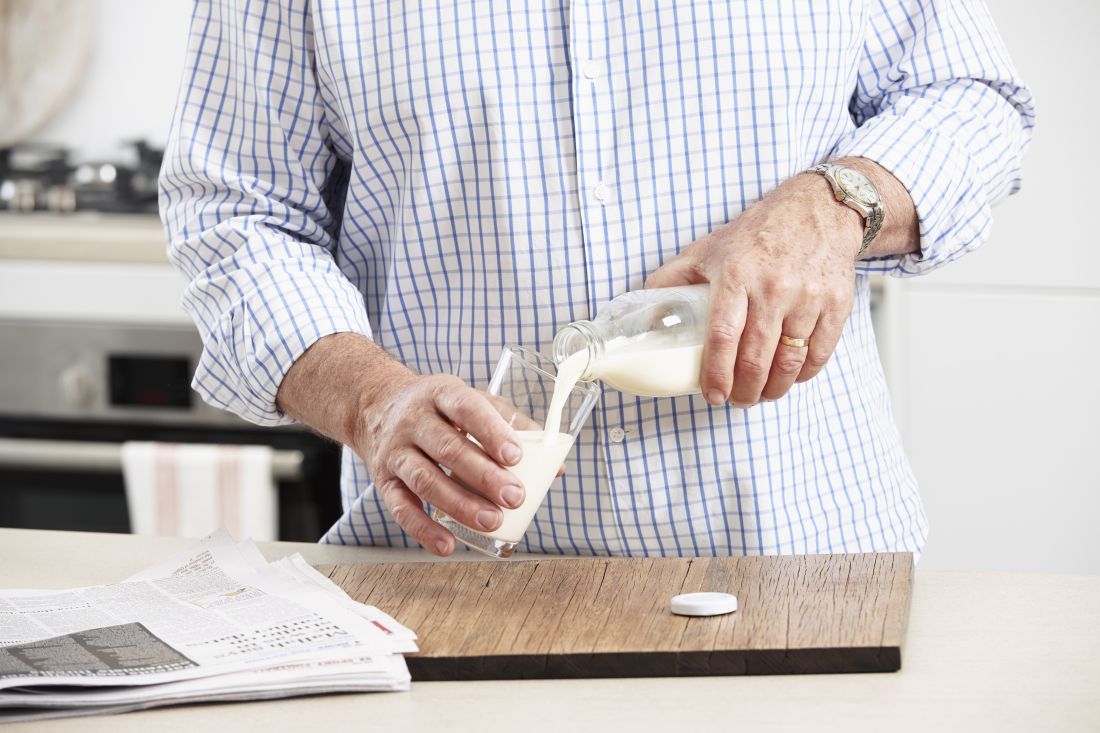 A man in a checked shirt pours milk from a bottle