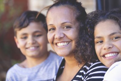 A portrait of a smiling woman with two children also smiling on either side of her