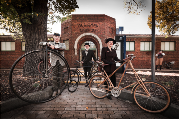 Image of cycling enthusiasts with penny farthings in front of the Grainger Museum.