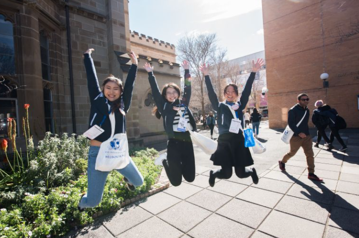 Three students jumping at Old Quad