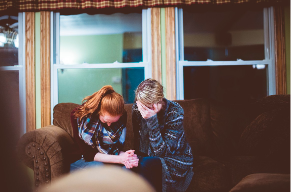Image of two aggreived women  sitting with heads down.