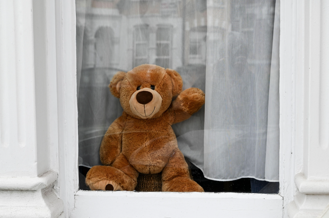 Teddy bear smiles in a window