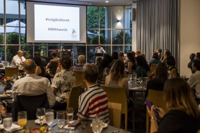 Crowd looks at the screen in front of them with information about the Indigenous Business Month Awards on it