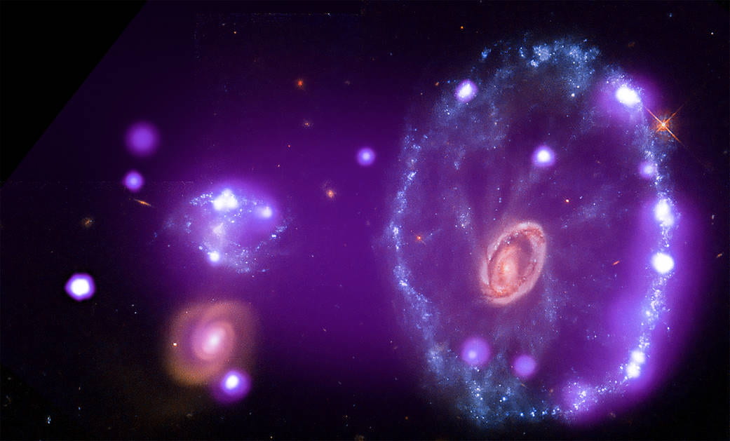 purple toned image of two galaxies. The one to the right is much larger.