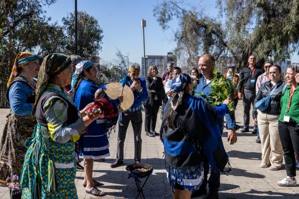 Deputy Vice-Chancellor Professor Barry Judd surrounded by people with instruments and wearing traditional dress during a Mapuche ritual